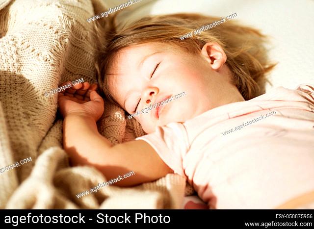 Sleeping little girl. Carefree sleep little baby with a soft toy on the bed. Close-up portrait of a beautiful sleeping child on knitted blanket