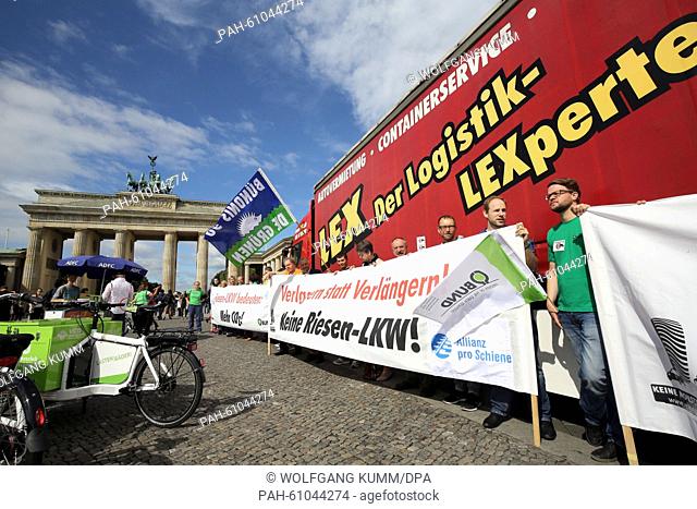 People hold up a banner that reads 'Riesen-LKW bedeuten: Mehr CO2!' (lit. Super trucks equal: More CO2!) next to a truck during a rally against so-called...