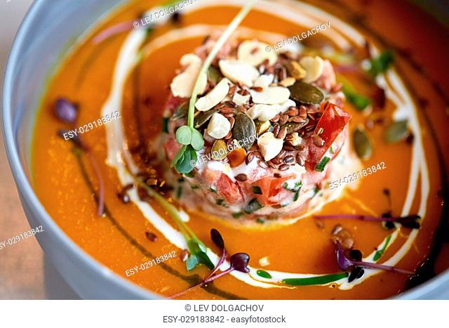 food, new nordic cuisine, culinary and cooking concept - close up of vegetable pumpkin-ginger soup with goat cheese and tomato salad with yogurt in bowl
