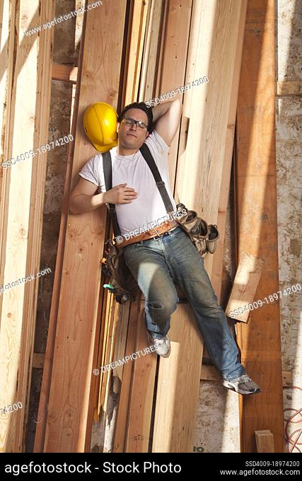 Aerial view of a man taking a nap on planks of wood at a residential construction site