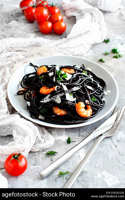 Squid ink black spaghetti with prawns and tomatoes close up