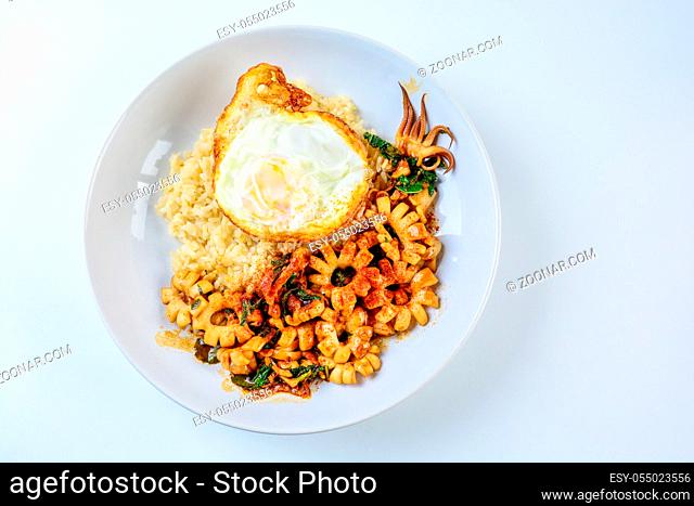 Spicy stir fried squid with basil leaves and chili, Sunny side up egg, served with brown rice. Hot and spicy dish