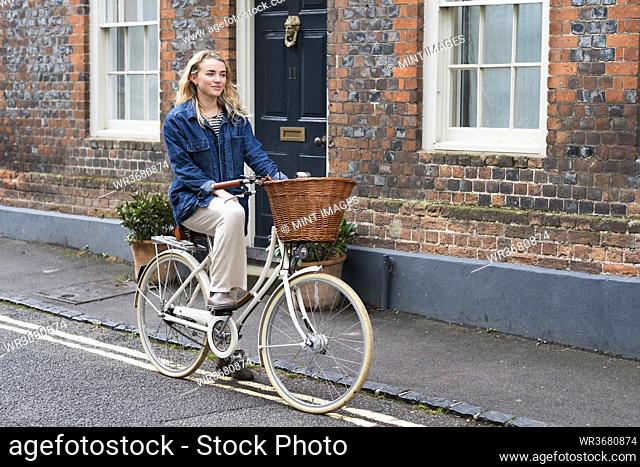 Young blond woman cycling down a village street