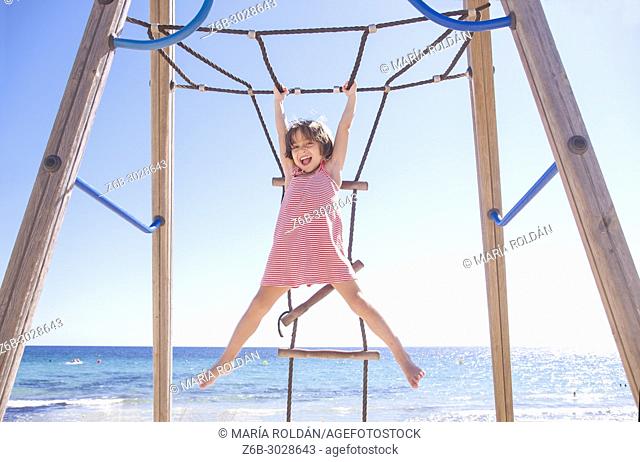 Little girl playing Monkey bars on the beach