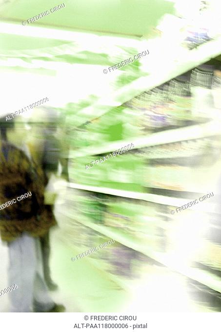 People looking at shelves in grocery store, blurred