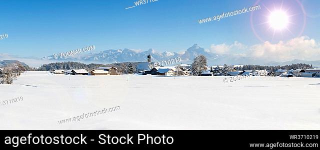 panoramic landscape in winter wirh mountain range and sun on sky