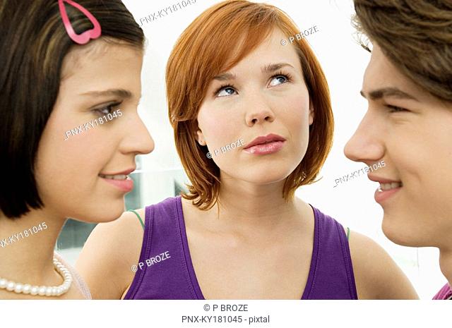 Side profile of a teenage boy looking at a young woman with another young woman looking up