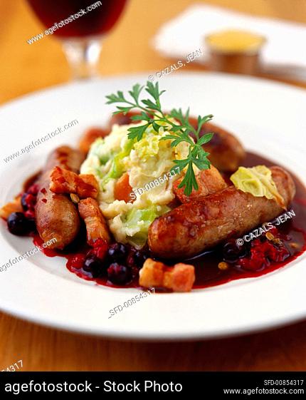 Sausages with mashed potato, bacon and blueberry sauce