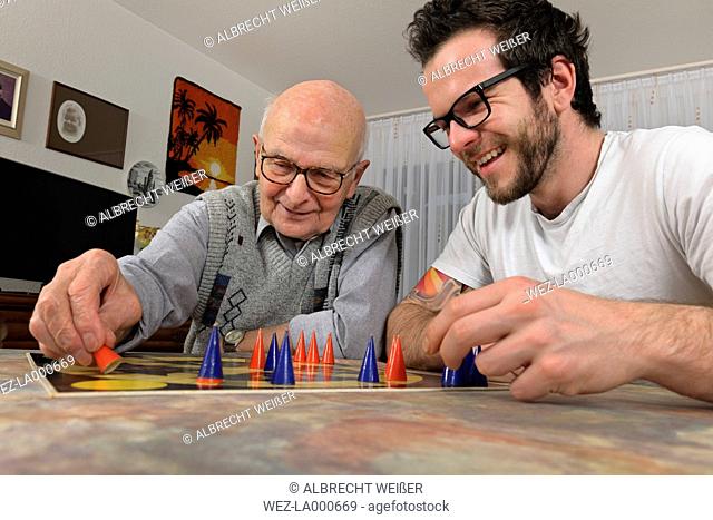 Grandfather and grandson playing together Trap the Cap at home