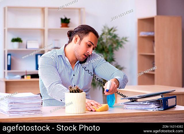 Young employee businessman cleaning office during pandemic