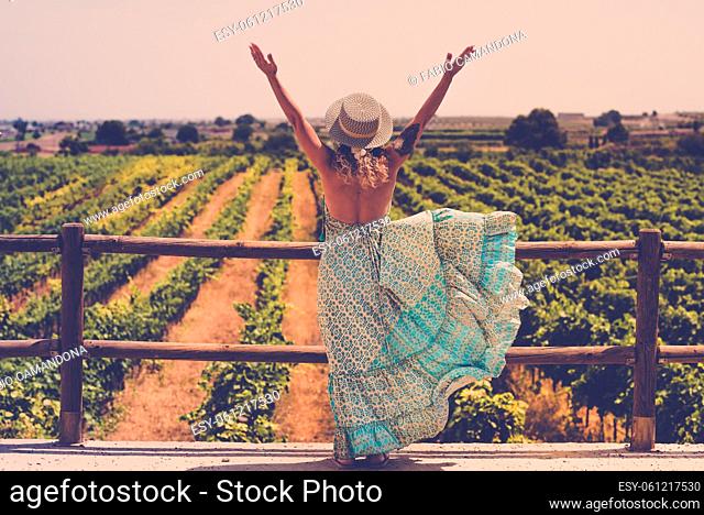 Trendy boho chic style back of woman opening arms for freedom feeling in front of a beautiful vineyard landscape - concept of outdoor and travel people...