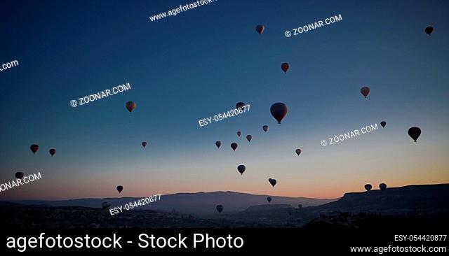 Sunrise panoramic view to Goreme city and flying balloons over pigeon valley Cappadocia, Turkey