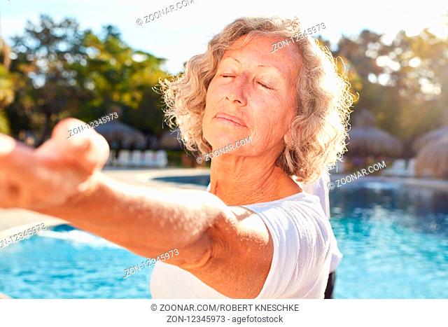 Senior Frau macht eine Yoga Meditation am Pool im Wellness Workshop