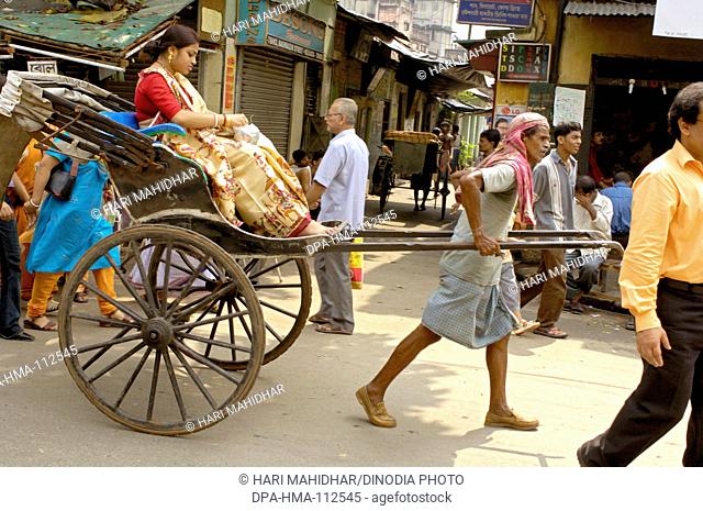 City life ; hand rickshaw puller pulling with passenger on street of Calcutta now Kolkata ; West Bengal ; India
