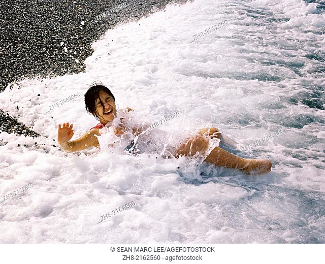 A young girl playing in the waves on a beach in Taiwan during the summer