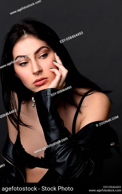 Picture of beautiful brunnette model woman posing in black lingerie or underwear and leather jacket in studio. Fashion or vogue concept