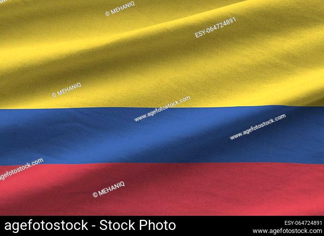 Colombia flag with big folds waving close up under the studio light indoors. The official symbols and colors in fabric banner