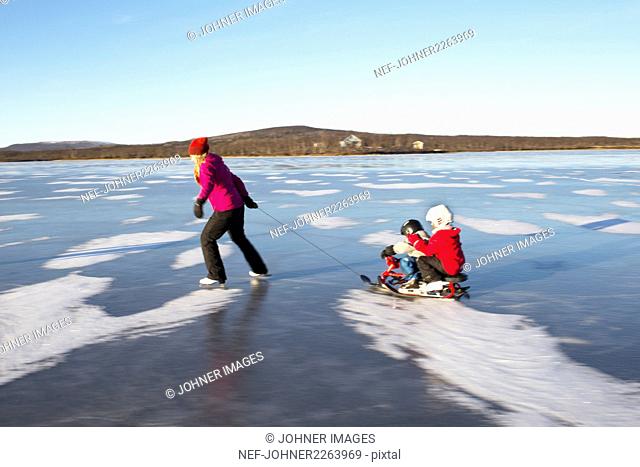 Mother pulling children on sledge
