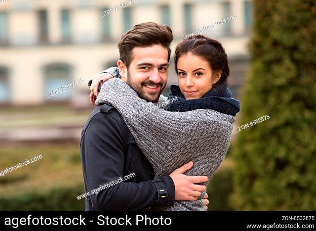 Portrait of happy couple hugging in the autumn park and looking at the camera. Happy couple spending weekends