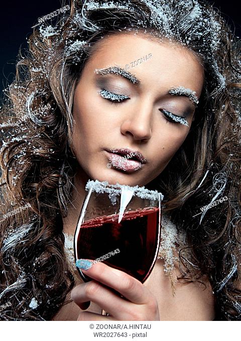 Portrait of young woman with snow make-up with a glass of wine. Christmas snow queen