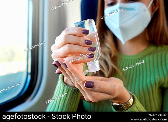 Business woman with medical face mask using alcohol gel sanitizing hands on public transport. Antiseptic, hygiene and health care concept