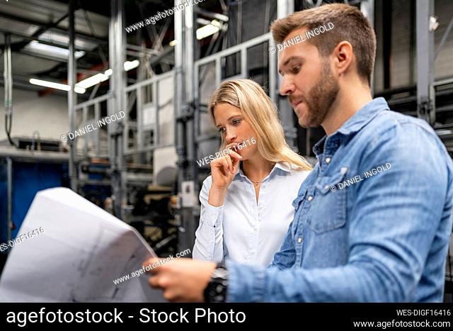 Business professionals brainstorming over plan in factory