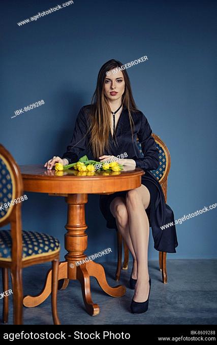 Beautiful young woman stands behind the table with tulips