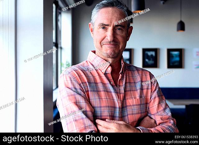 Portrait of confident mature caucasian businessman with arms crossed in creative office