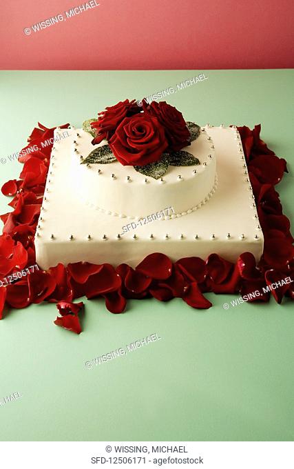 A wedding cake decorated with silver pearls and rose petals