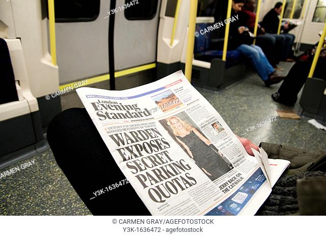 Someone reading the Evening Standard london free newspaper in the tube