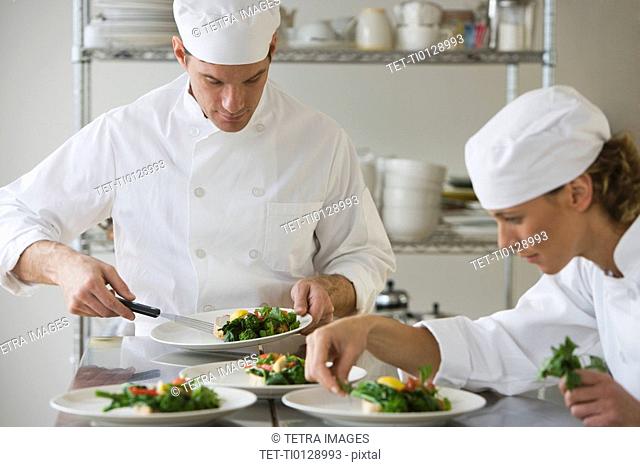 Male and female chefs plating food