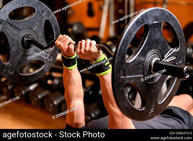 Handsome young muscular man close up, doing bench french press workout with barbell in gym