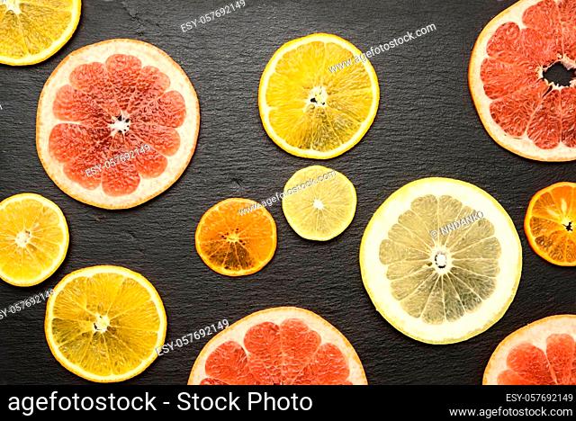 citrus fruits cut into round pieces: orange, grapefruit, lemon, tangerine. Ripe and juicy fruits on black background
