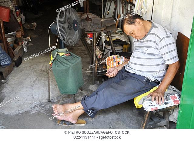 Malacca (Malaysia): a man sleeping in his antique shop, in front of a fan, in Chinatown