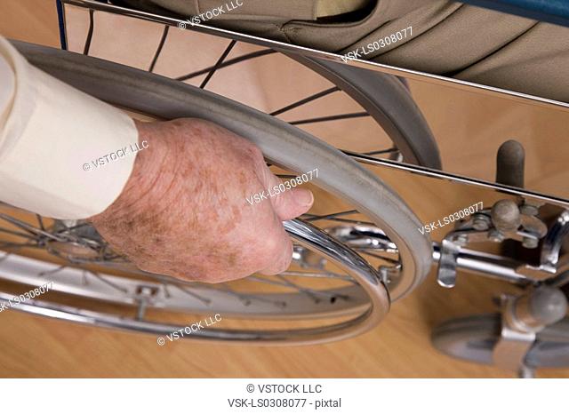 Close-up of senior man's hand on wheel chair