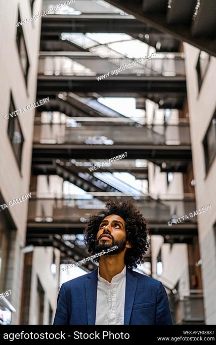 Male entrepreneur looking up while standing amidst buildings