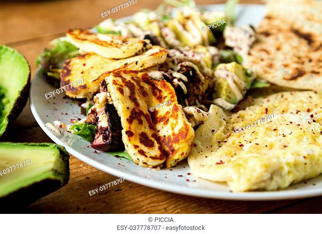 Middle Eastern cuisine: delicious plate of grilled halloumi cheese served with a lettuce and avocado salad, seasoned with sumac and other spices
