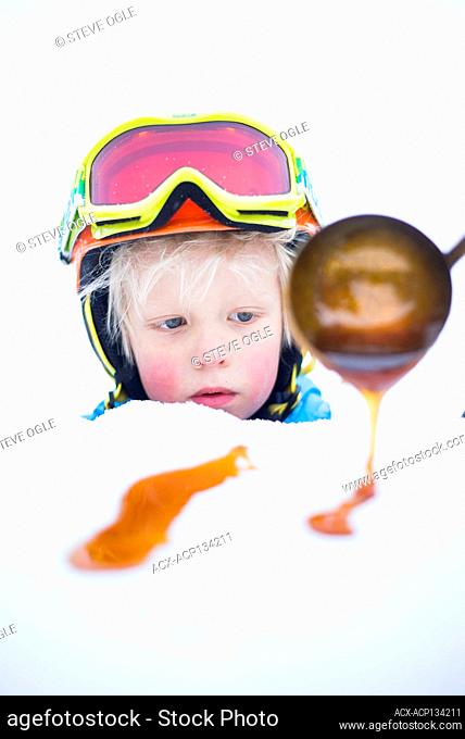 A young boy enjoys some maple taffy or tire d'érable during a winter carnival in Nelson, British Columbia
