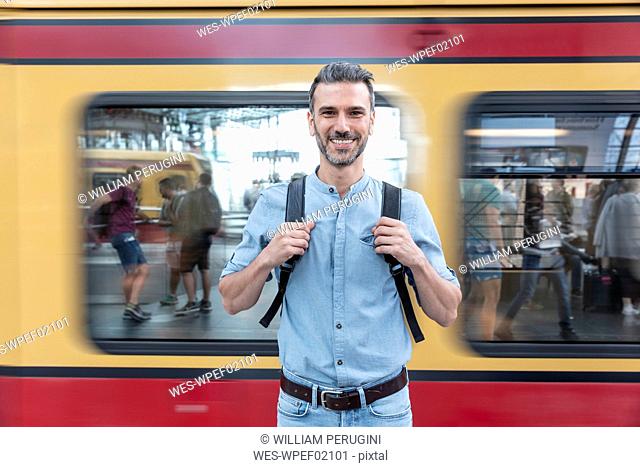 Portrait of smiling man at the station platform with train in background