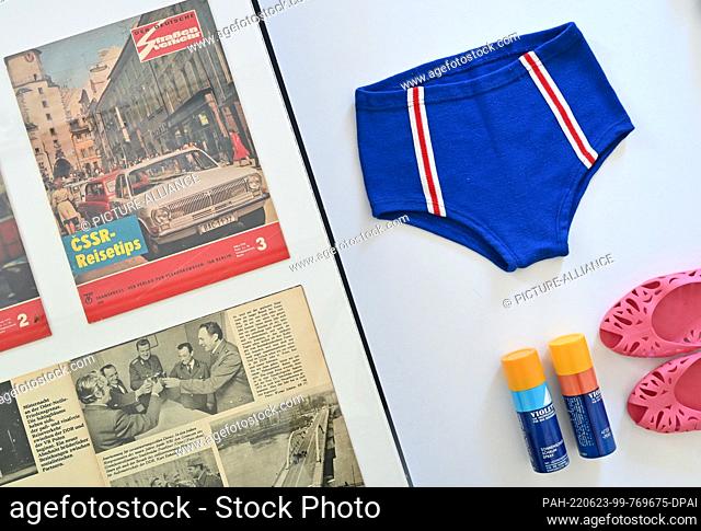 23 June 2022, Brandenburg, Eisenhüttenstadt: A pair of swimming trunks from VEB Strickwaren Oberlungwitz from the 1970s, ""Carola"" bathing shoes and...