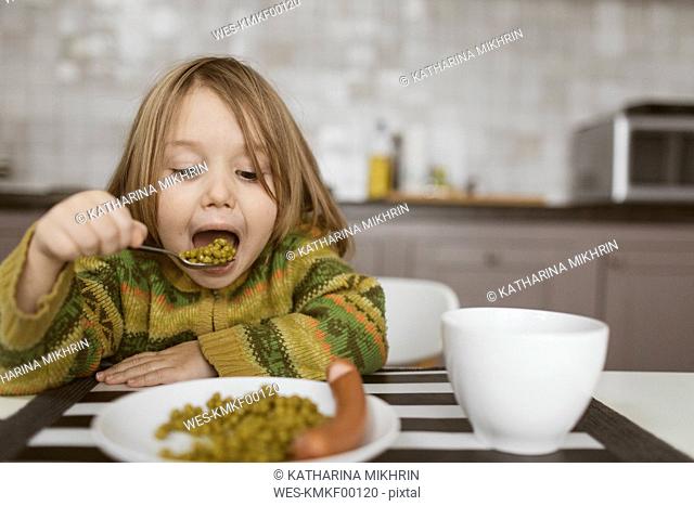 Portrait of little girl having lunch in the kitchen