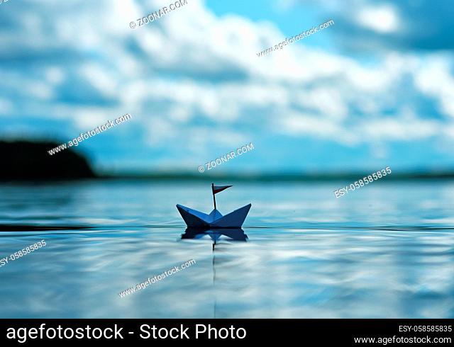 Kleines Papierschiff auf glitzerndem See