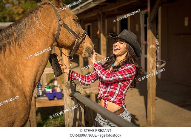 Cowgirl showing affection to horse on ranch
