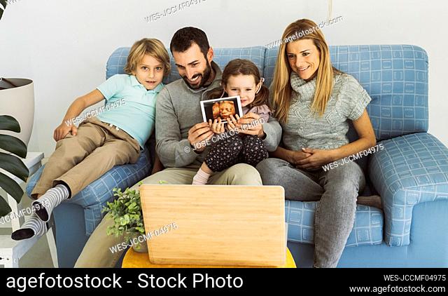 Smiling family with ultrasound on video call through laptop at home