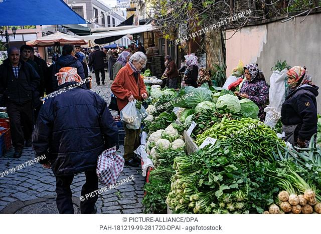 11 December 2018, Turkey, Tire: Market day in Tire in the Turkish province of Izmir. A woman buys fresh vegetables at a market stall