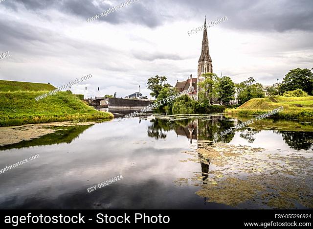 Church reflected on water pond in Churchill Park in Copenhagen a cloudy day of summer near sunset