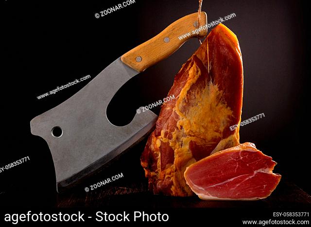Luxurious meat background. Smoked prosciutto ham with butcher cleaver