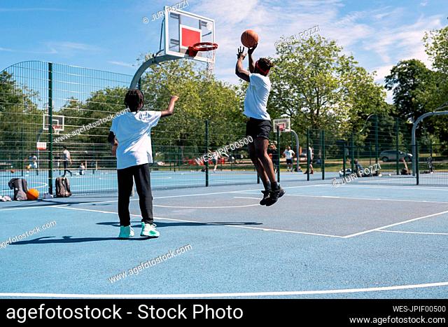 Father and son playing basketball on basketball court