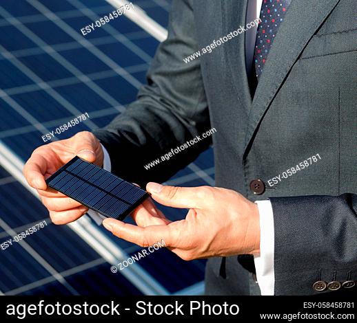Businessman holding photovoltaic element in his hands. Close up view on photovoltaic detail of solar panel in mans hands