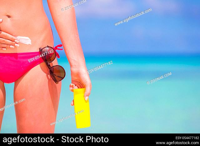Young woman apply cream on her nose at beach